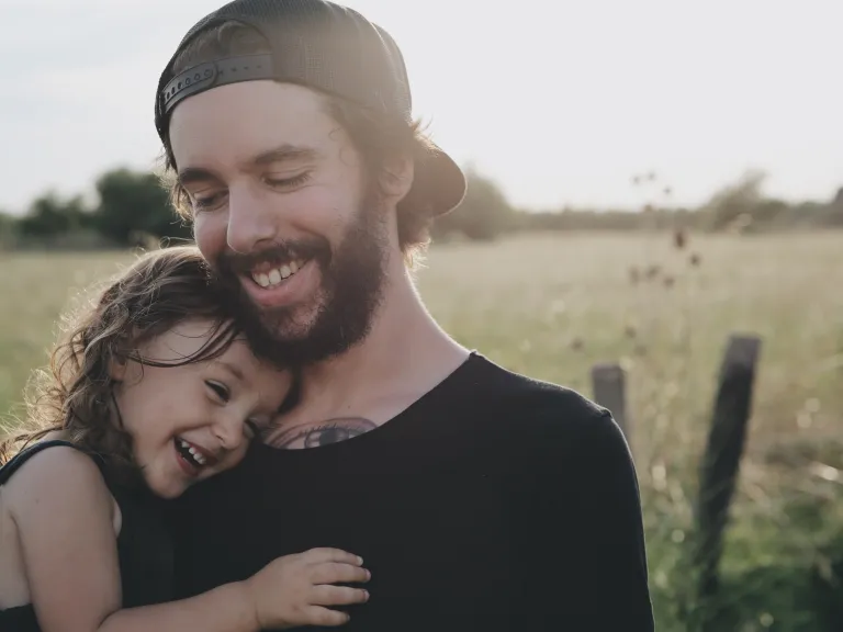 A dad hugs his daughter and they laugh together