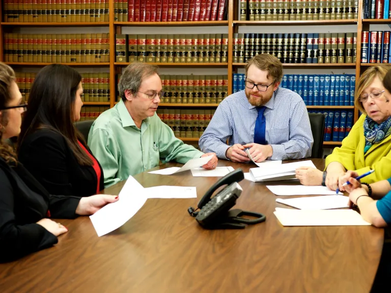 A group situated around a table looking at paperwork